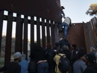 Immigrant Caravan Members Continue To Gather At U.S.-Mexico Border TIJUANA, MEXICO - DECEMBER 02: A woman climbs atop a fellow member of the migrant caravan while crossing over the U.S.-Mexico border fence on December 2, 2018 from Tijuana, Mexico. Numerous members of the caravan were able to pass from Tijuana to San Diego and were quickly taken into custody …