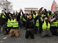 PARIS, FRANCE - DECEMBER 08: Demonstrators kneel and gesture with victory signs as they take part in the demonstration of the yellow vests at the Arc de Triomphe on December 08, 2018 in Paris France. ''Yellow Vests' ('Gilet Jaunes' or 'Vestes Jaunes') is a protest movement without political affiliation which …