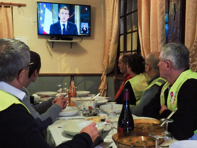 Yellow vest (gilets jaunes) protestors take notes as thet watch French President Emmanuel Macron's speech on TV on December 10, 2018 at a restaurant with French deputy Richard Damos, in Fay-au-Loges, near Orleans, Center France. (Photo by GUILLAUME SOUVANT / AFP) (Photo credit should read GUILLAUME SOUVANT/AFP/Getty Images)