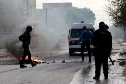 Tunisian policemen stand in a street during a demonstration on December 25, 2018 in the central Tunisian city of Kasserine. - A Tunisian journalist has died after setting himself on fire, officials said, in a protest over harsh living conditions that prompted overnight clashes with police in the country's west. …