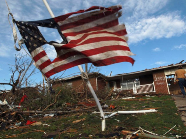 JOPLIN, MO - MAY 27: A torn American flag hangs on a pole outside of a house that was damaged during a massive tornado on May 27, 2011 in Joplin, Missouri. At least 125 were killed and 232 remain missing after the EF-5 tornado ripped through the town of about …