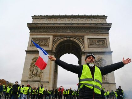 TOPSHOT - A demonstrator waves a French national flag during a protest of Yellow vests (Gilets jaunes) against rising oil prices and living costs in front of the Arc of Triomphe on the Champs Elysees avenue in Paris, on December 1, 2018. - Thousands of anti-government protesters are expected today …
