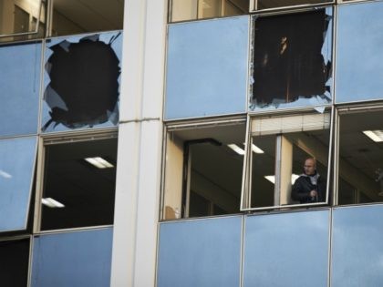 A journalist looks out a broken window after a powerful bomb exploded outside private Gree