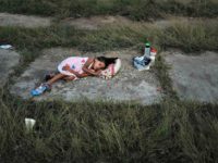 A child sleeps as members of the Central American caravan settle in for the night in an abandoned mot A child sleeps as members of the Central American caravan settle in for the night in an abandoned mot