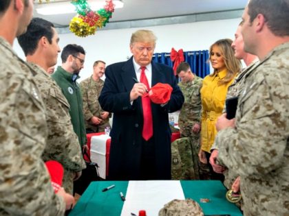 US President Donald Trump signs a hat as First Lady Melania Trump looks on as they greet members of the US military during an unannounced trip to Al Asad Air Base in Iraq on December 26, 2018. - President Donald Trump arrived in Iraq on his first visit to US …