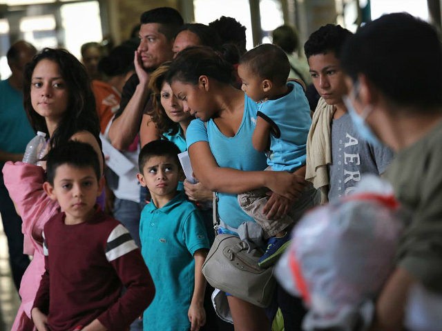 MCALLEN, TX - AUGUST 15: Immigrants stand in line for a bus on August 15, 2016 in McAllen, Texas. Central American immigrant families, who had crossed into Texas through Mexico, are processed at a U.S. Border Patrol center, given temporary legal documents and sent to their destination city, while their …