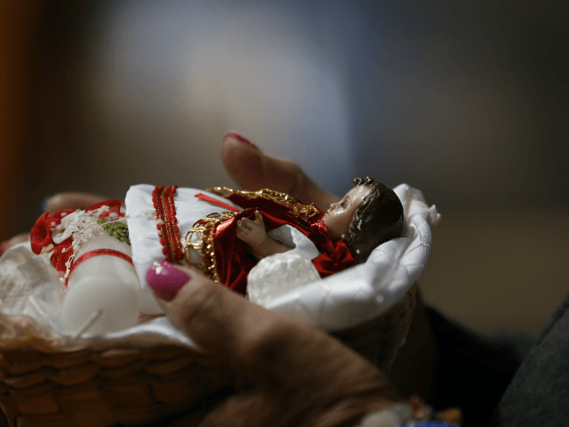 A woman takes her baby Jesus figurine to the altar to be blessed, inside the San Juan Baut