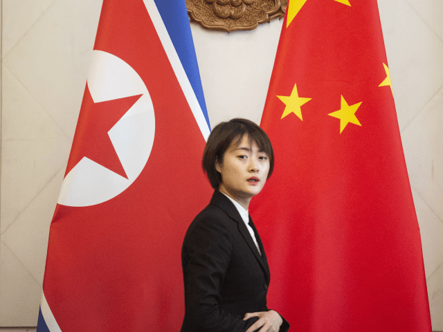 A Chinese hostess walks past North Korean and Chinese national flags before a meeting betw