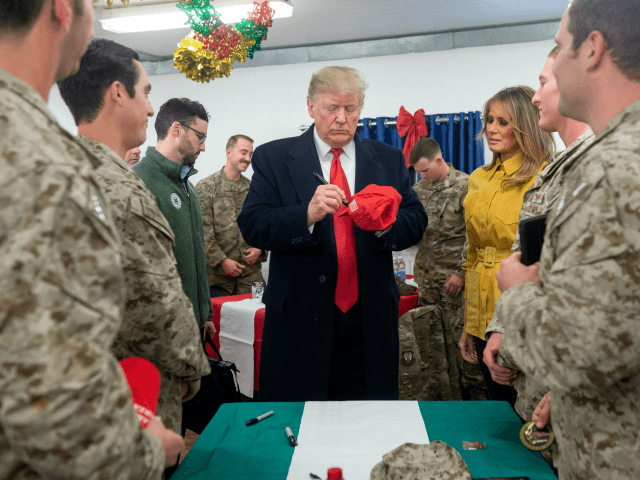 US President Donald Trump signs a hat as First Lady Melania Trump looks on as they greet members of the US military during an unannounced trip to Al Asad Air Base in Iraq on December 26, 2018. - President Donald Trump arrived in Iraq on his first visit to US …