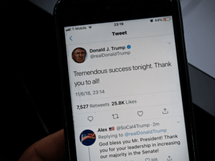 A smartphone shows a tweet by US President Donald Trump saying 'Tremendous success tonight