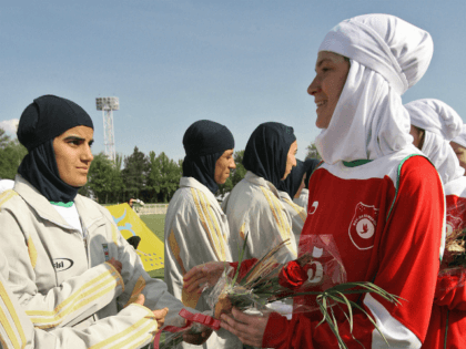 Players from Iran's women national football team (white) exchange flowers with players from Germany's Al-Dersimspor team before a friendly match at Tehran's Ararat stadium 28 April 2006. Hardline President Mahmoud Ahmadinejad announced this week that Iranian women can go to stadiums to watch sporting events, putting an end to a …
