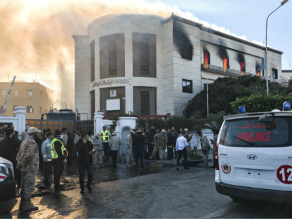 A picture taken on December 25, 2018 shows ambulances, paramedics, and security officers at the scene of an attack outside the Libyan foreign ministry headquarters in the capital Tripoli. - At least one person was killed on December 25 as attackers stormed Libya's foreign ministry after a car bomb exploded …