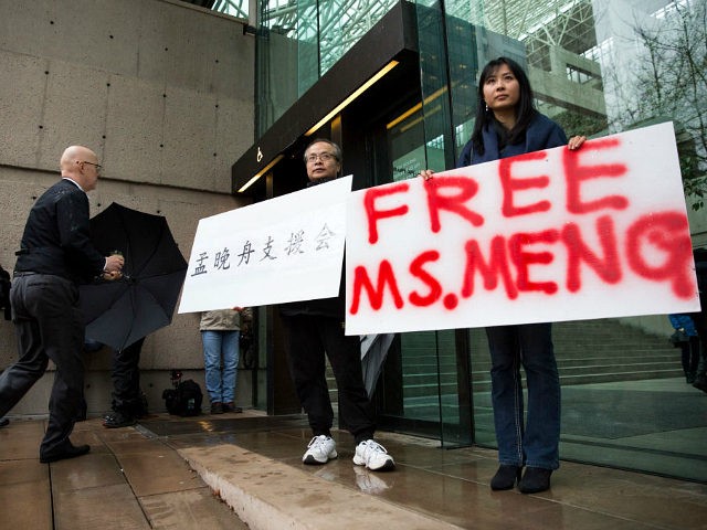 Robert Long (L) and Ada Yu hold signs in favor of Huawei Technologies Chief Financial Officer Meng Wanzhou outside her bail hearing at British Columbia Superior Courts following her December 1 arrest in Canada for extradition to the US, in Vancouver, British Columbia on December 11, 2018. (Photo by Jason …
