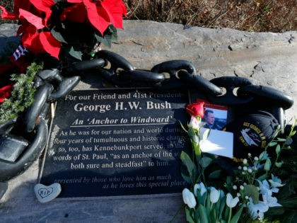lowers and mementoes lay near a plaque honoring former President George H. W. Bush at a makeshift memorial across from Walker's Point, the Bush's summer home, Saturday, Dec. 1, 2018, in Kennebunkport, Maine. Bush died at the age of 94 on Friday, about eight months after the death of his …