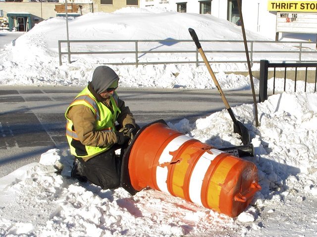 Jason Gion, an employee for the city of Fargo, N.D., works in 15-below temperatures while repairing a warning cone meant to prevent drivers from running into a sidewalk barrier at a road construction project near the city's downtown on Friday, Jan. 25, 2019. The warning cone was damaged after a …