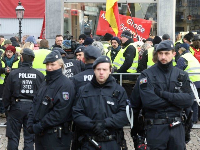 Policemen secure the area as people wearing yellow vests stand outside the town hall of Aachen, western Germany, where is taking place a signing ceremony of a French-German friendship treaty, on January 22, 2019. - France and Germany signed a new friendship treaty seeking to boost an alliance at the …