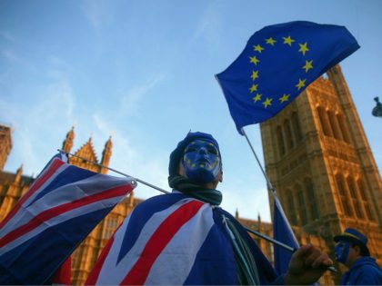 A pro-European Union, (EU), anti-Brexit demonstrator wears a mask featuring the EU flag as he holds Union and EU flags outside the Houses of Parliament in central London on December 18, 2017. (Photo by Daniel LEAL-OLIVAS / AFP) (Photo credit should read DANIEL LEAL-OLIVAS/AFP/Getty Images)