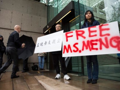 Robert Long (L) and Ada Yu hold signs in favor of Huawei Technologies Chief Financial Officer Meng Wanzhou outside her bail hearing at British Columbia Superior Courts following her December 1 arrest in Canada for extradition to the US, in Vancouver, British Columbia on December 11, 2018.