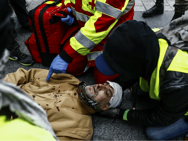 TOPSHOT - A firefighter helps an injured man near the Champs Elysees avenue in Paris on December 8, 2018 during a mobilisation against rising costs of living they blame on high taxes. - Paris was on high alert on December 8 with major security measures in place ahead of fresh …