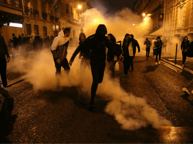 'Yellow vest' protestors (Gilets jaunes) and others run as police use tear gas to disperse them on a side street off the Champs-Elysees after New Year's celebrations in the French capital Paris on January 1, 2019. - A fireworks display and sound and light show under the theme 'fraternity' went …