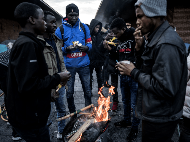 Asylum seekers from eastern African countries - mainly Sudan - warm themselves up around a