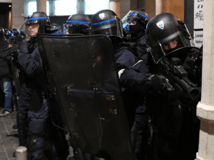 A police officer points a non-lethal hand-held weapon at protesters in front of the Cathed