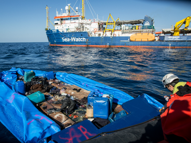 A Sea Watch 3 crew member marks with spray paint a rubber boat that the NGO destroyed after rescuing 47 migrants that were onboard, during a rescue operation by the Dutch-flagged vessel (Rear) off Libya's coasts on January 19, 2019. - The German charity group Sea Watch said on January …
