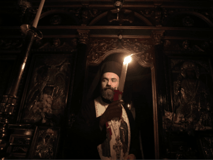 An Orthodox priest gives the Holy Fire to worshippers with a candle inside the Church of Metochi Panagiou Tafou in Athens, on April 15, 2017. The Holy Fire arrived from the church of the Holy Sepulcher in Jerusalem, earlier this evening. Greeks flock to churches around the country this week …