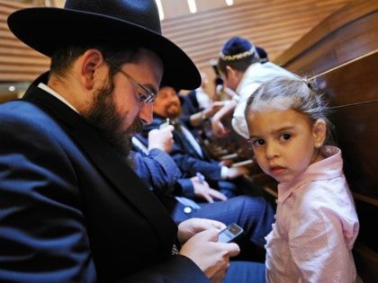 BERLIN, GERMANY - JUNE 19: A young girl looks on as her father checks his iPhone prior to an ordination ceremony for six rabbinical students at Gedola Yeshiva at the Chabad Education Center on June 19, 2011 in Berlin, Germany. Rabbinical centers across Germany are generating a new generation of …