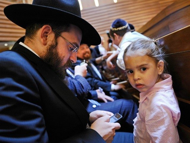 BERLIN, GERMANY - JUNE 19: A young girl looks on as her father checks his iPhone prior to