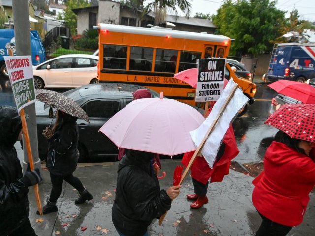 A school bus arrives with students as teachers and their supporters picket outside John Ma