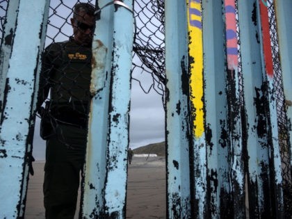 A border patrol agent checks on the US-Mexico border fence as seen from Playas de Tijuana,