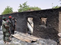 Nigeria-Unrest-Islamists-Gubio Anti-riot policemen look at a burnt mud house in Gubio in Borno State, northeast Nigeria, on May 26, 2015. A weekend attack by Boko Haram in the northeast Nigerian town of Gubio left 37 people dead, with more than 400 buildings destroyed by fire, local vigilantes said on May 26. …
