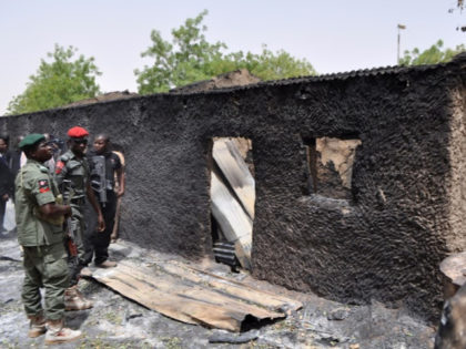Anti-riot policemen look at a burnt mud house in Gubio in Borno State, northeast Nigeria, on May 26, 2015. A weekend attack by Boko Haram in the northeast Nigerian town of Gubio left 37 people dead, with more than 400 buildings destroyed by fire, local vigilantes said on May 26. …