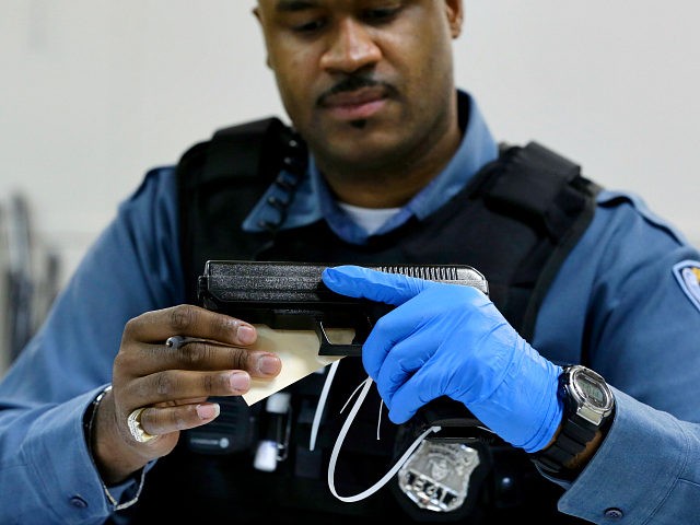 Trenton police officer Kozell Hodges examines a pistol Friday, Jan. 25, 2013, in Trenton,