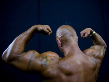 In this Thursday, Oct. 18, 2018 photo, a contestant exercises backstage during the National Amateur Body Builders' Association competition in Tel Aviv, Israel. Exhausted from weeks of strict dieting and last-minute exertions, the muscle-bound athletes primped, painted and prepped before taking the stage. (AP Photo/Oded Balilty)