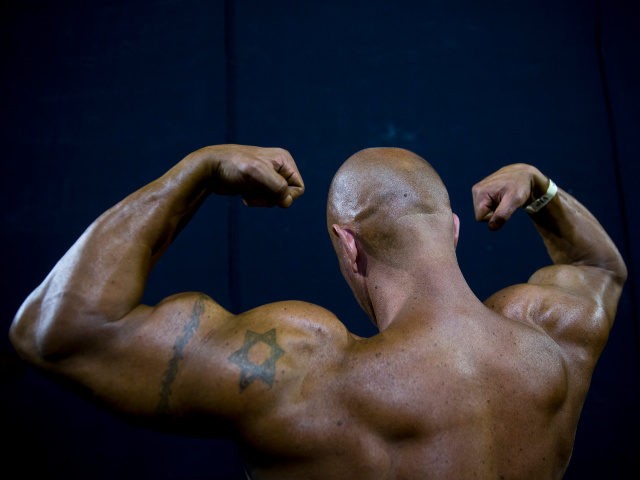 In this Thursday, Oct. 18, 2018 photo, a contestant exercises backstage during the National Amateur Body Builders' Association competition in Tel Aviv, Israel. Exhausted from weeks of strict dieting and last-minute exertions, the muscle-bound athletes primped, painted and prepped before taking the stage. (AP Photo/Oded Balilty)