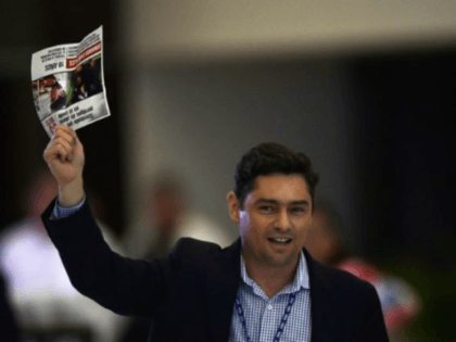 Exiled Venezuelan opposition leader Carlos Vecchio, holding up a newspaper article about o