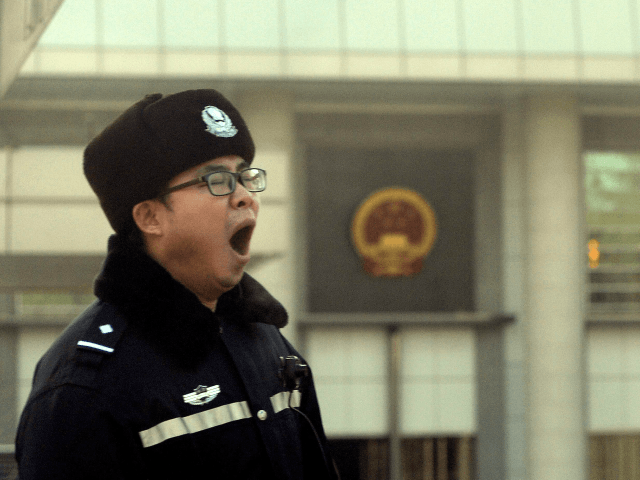 Right to remain silent: A policeman yawns while standing guard outside the Beijing court w