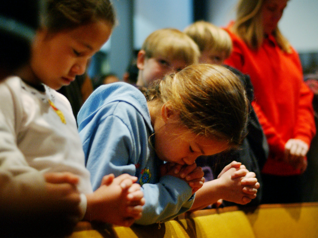 Susan (no last names released) bows her head in prayer as she and fellow fourth-grader Car