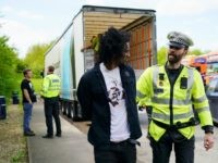 illegal alien OXFORD, ENGLAND - MAY 03: Police officers arrest two men, believed to be migrants, who were stowed away in the back of a Polish lorry at Oxford Services on the M40 motorway on May 3, 2018 in Oxford, England. The truck was escorted off the M40 motorway by police where …