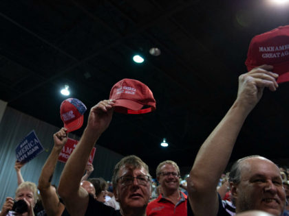 Supporters hold up their 'Make America Great Again' hats as US President Donald Trump speaks during a campaign rally at Florida State Fairgrounds Expo Hall in Tampa, Florida, on July 31, 2018. (Photo by SAUL LOEB / AFP) (Photo credit should read SAUL LOEB/AFP/Getty Images)