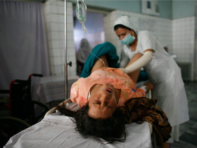 An Afghan mother grimaces as a nurse checks her after a difficult delivery outside the ope