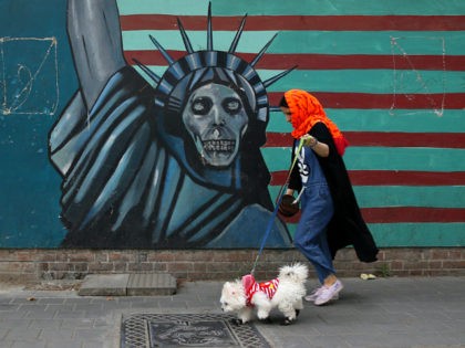 A woman walks her dog past an anti-U.S. mural painted on the wall of the former U.S. Embassy in Tehran, Iran, Tuesday, May. 8, 2018. President Donald Trump prepared to tell the world Tuesday whether he plans to follow through on his campaign threat to pull out of the landmark …