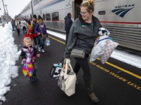 Jordyn Hooper, right, and her four-year-old daughter Quinn Hooper, left, join other passengers as they disembark from an Amtrak train in Eugene, Ore, Tuesday, Feb. 26, 2019 after being stranded overnight in the mountains east of town. (AP Photo/Chris Pietsch)