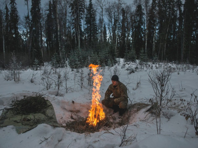 Staff Sgt. Seth Reab, an Arctic Survival School instructor, creates a small fire with a pi