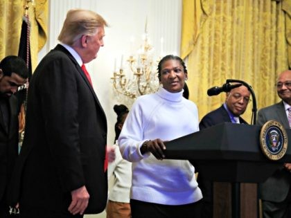 President Donald Trump listens to Catherine Toney speak during a National African American