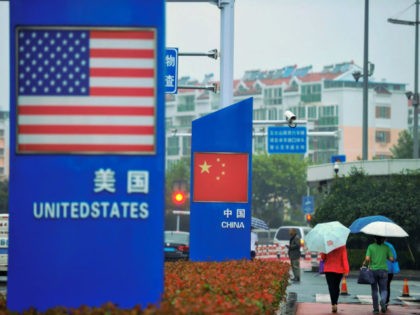 Signs with the US flag and Chinese flag are seen outside a store selling foreign goods in Qingdao in China's eastern Shandong province on September 19, 2018. - China on September 18 announced tariffs on US goods worth $60 billion in retaliation for President Donald Trump's decision to slap duties …