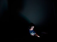 Child-plays-with-smartphone A child plays with a smartphone in his bedroom in San Salvador on October 7, 2018.