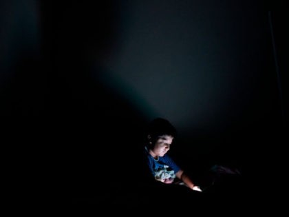 A child plays with a smartphone in his bedroom in San Salvador on October 7, 2018.